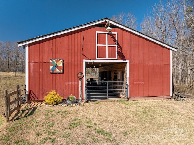 view of barn with fence and a lawn