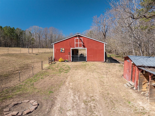 view of outbuilding with fence and an outbuilding