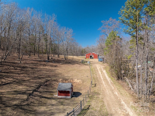 view of street with a barn, dirt driveway, and a rural view