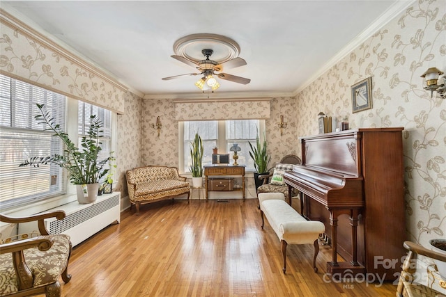 living area featuring crown molding, ceiling fan, and light hardwood / wood-style flooring