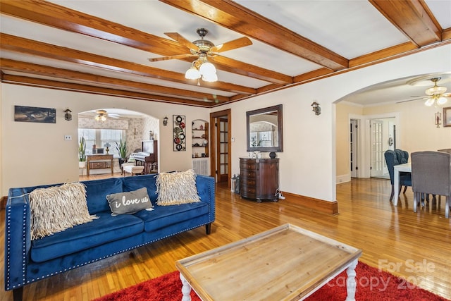 living room with hardwood / wood-style flooring, ceiling fan, ornamental molding, and beam ceiling