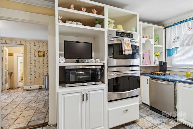 kitchen with white cabinetry, ornamental molding, tile counters, and stainless steel appliances