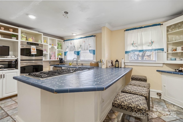 kitchen with sink, appliances with stainless steel finishes, ornamental molding, white cabinets, and tile countertops