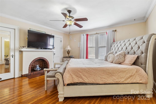 bedroom with wood-type flooring, a brick fireplace, and crown molding