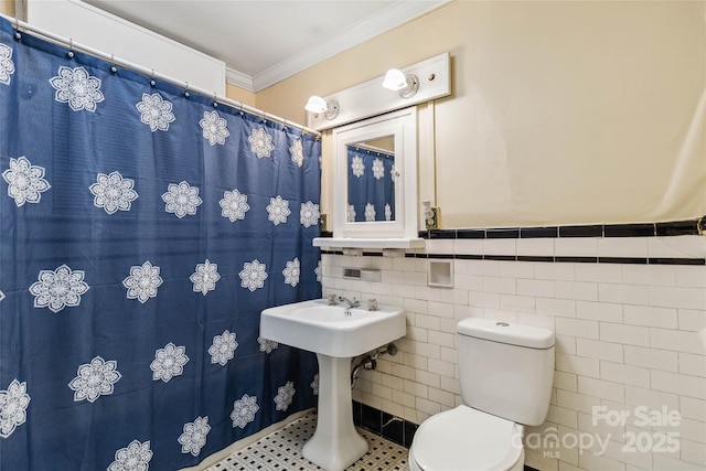 bathroom featuring crown molding, toilet, and tile walls