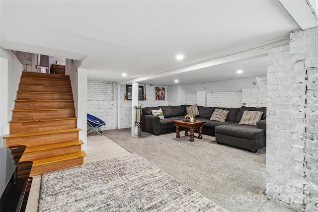 carpeted living room featuring brick wall