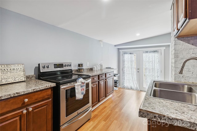 kitchen with stainless steel electric stove, french doors, lofted ceiling, sink, and light hardwood / wood-style flooring