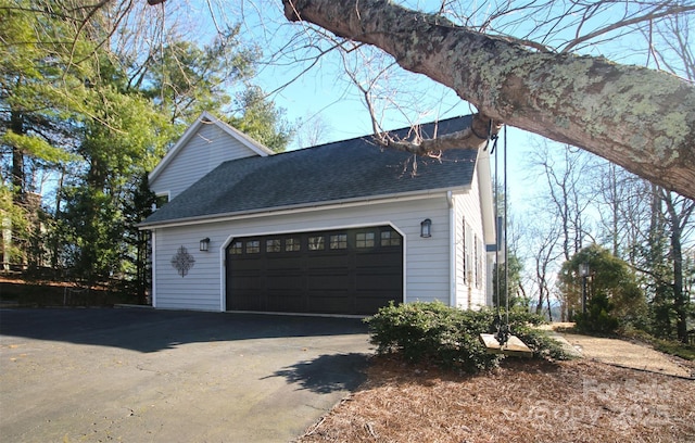 view of side of home with a garage and roof with shingles