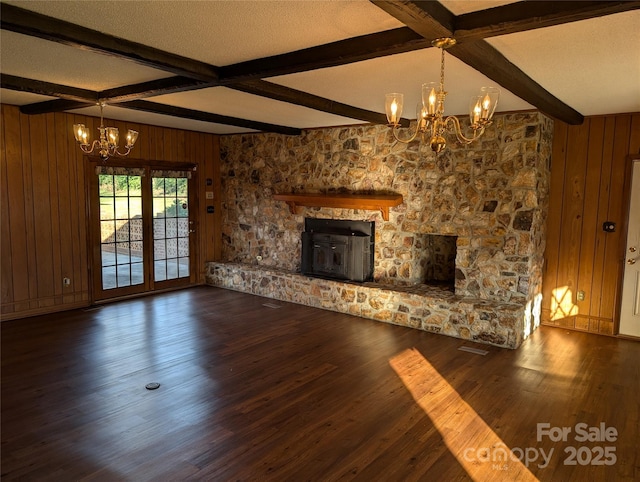 unfurnished living room featuring beamed ceiling, dark wood-type flooring, a notable chandelier, and a textured ceiling