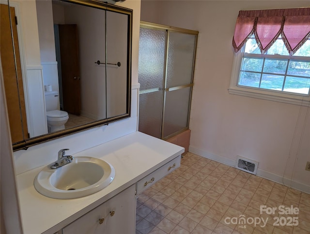 full bathroom featuring enclosed tub / shower combo, vanity, and toilet