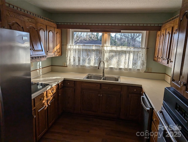 kitchen with sink, stainless steel refrigerator, black electric stovetop, a textured ceiling, and dark hardwood / wood-style flooring