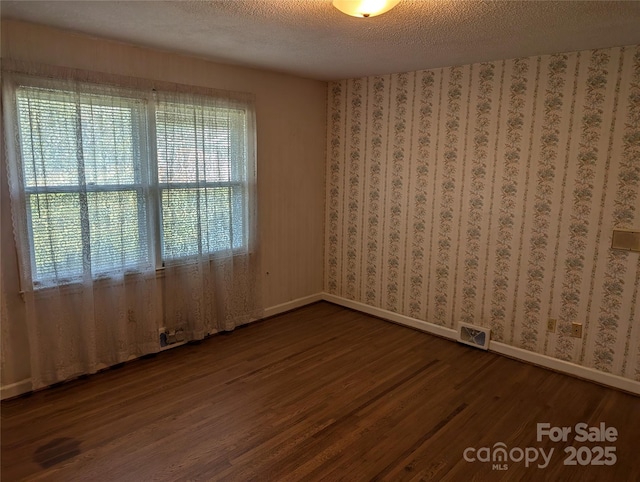 empty room with hardwood / wood-style floors and a textured ceiling