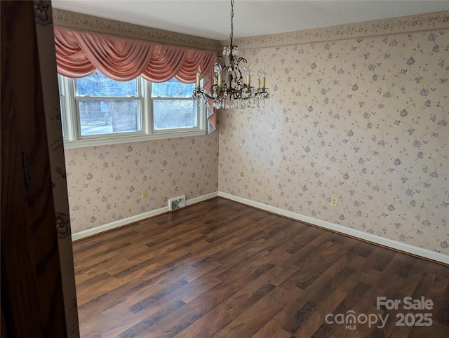 unfurnished dining area with dark wood-type flooring, an inviting chandelier, and a textured ceiling