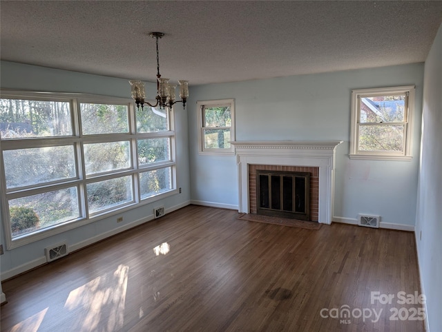 unfurnished living room with plenty of natural light, dark hardwood / wood-style floors, a textured ceiling, and a fireplace