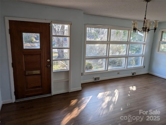 entryway featuring dark wood-type flooring, a notable chandelier, and a textured ceiling