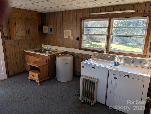 washroom with sink, washer and clothes dryer, plenty of natural light, and wood walls