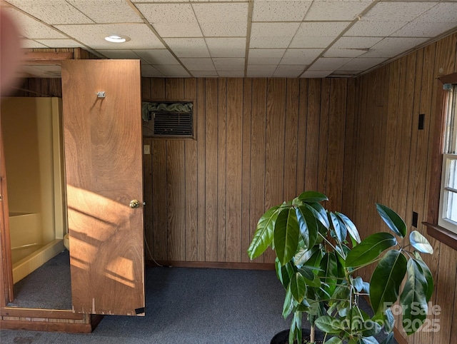 corridor with a drop ceiling and wood walls