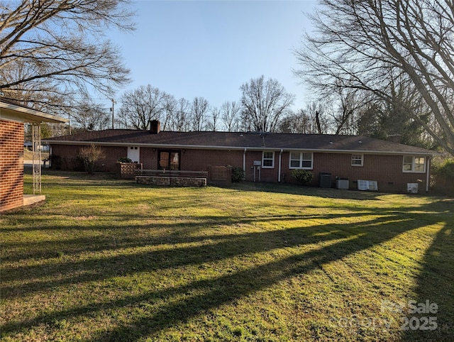 rear view of house featuring central AC unit and a lawn