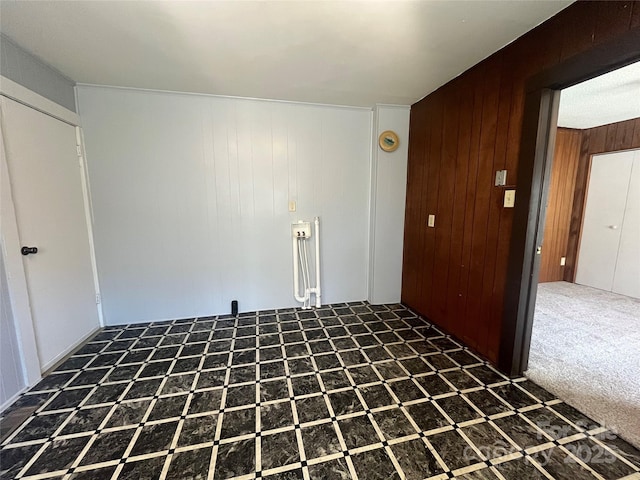 carpeted spare room featuring wooden walls