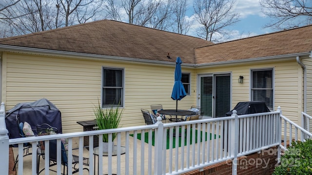 back of property featuring a deck and a shingled roof