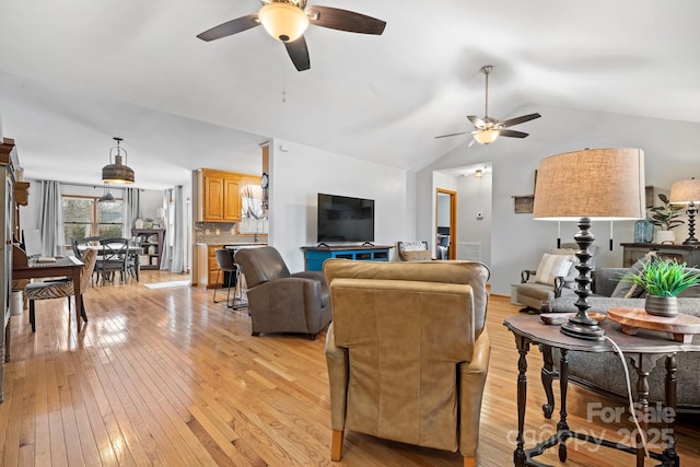 living room with lofted ceiling, light wood finished floors, and a ceiling fan