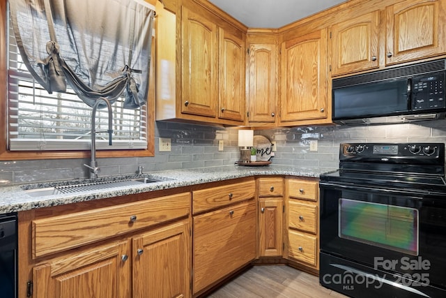 kitchen featuring tasteful backsplash, a sink, black appliances, and light stone countertops