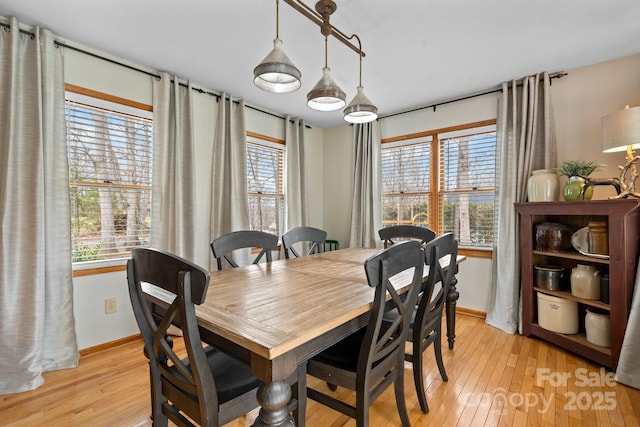 dining area featuring light wood-type flooring, plenty of natural light, and baseboards