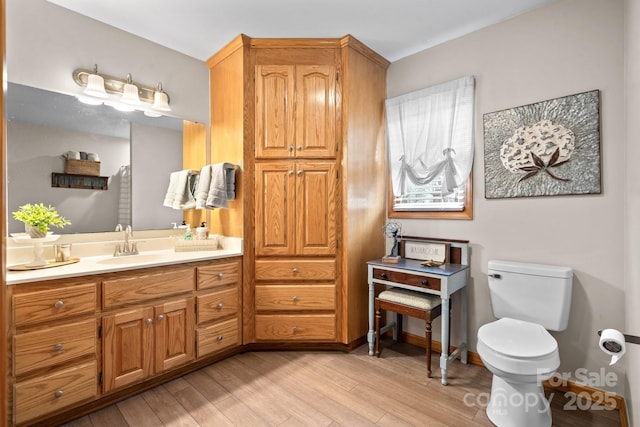 bathroom featuring vanity, wood finished floors, toilet, and baseboards