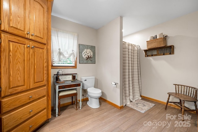 bathroom featuring a shower with curtain, wood finished floors, toilet, and baseboards