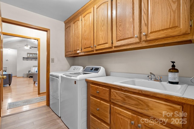 laundry area with light wood-style flooring, a sink, a ceiling fan, independent washer and dryer, and cabinet space