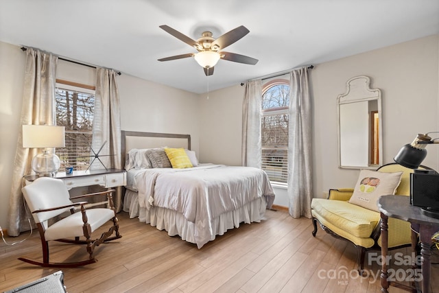 bedroom with a ceiling fan, multiple windows, and wood finished floors