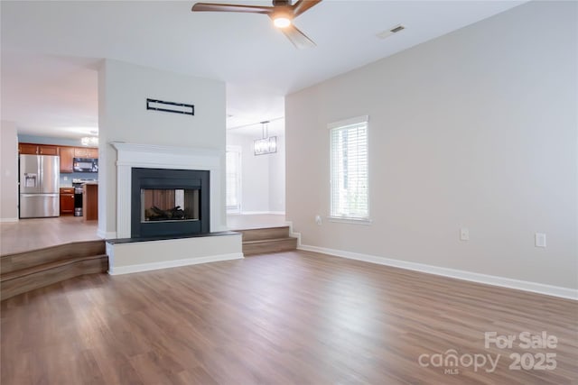 2043 Covered Bridge Ct, Rock Hill, SC 29732 - unfurnished living room featuring ceiling fan, wood finished floors, a chandelier, a fireplace with raised hearth, and baseboards