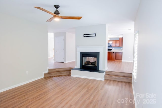 2043 Covered Bridge Ct, Rock Hill, SC 29732 - unfurnished living room featuring light wood finished floors, a ceiling fan, baseboards, and a multi sided fireplace