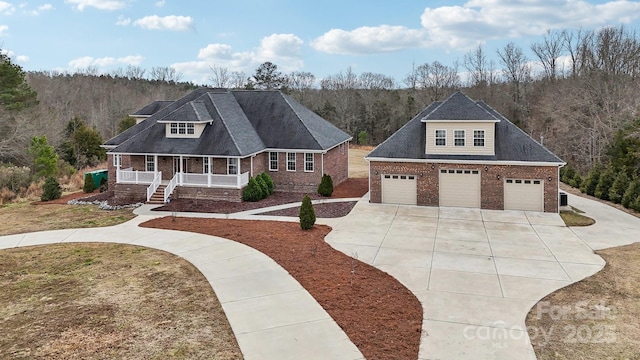 view of front of property featuring a porch, brick siding, driveway, and a garage