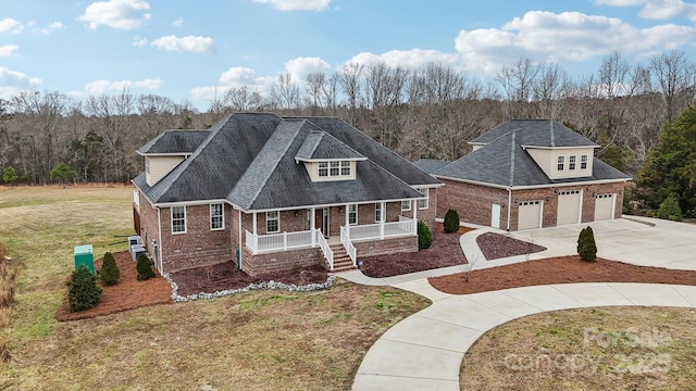 view of front of home featuring covered porch, brick siding, concrete driveway, a front lawn, and a view of trees