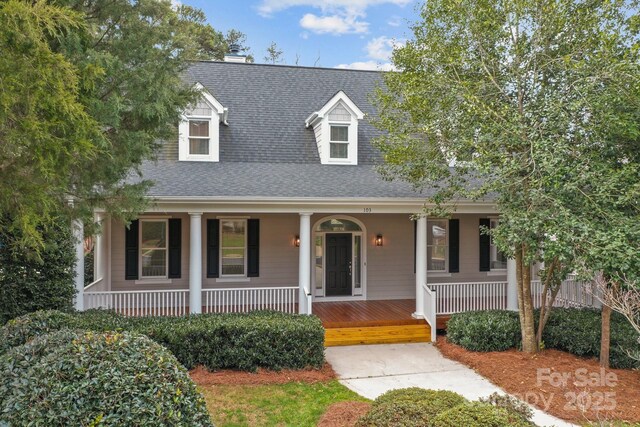 cape cod house featuring covered porch and a shingled roof