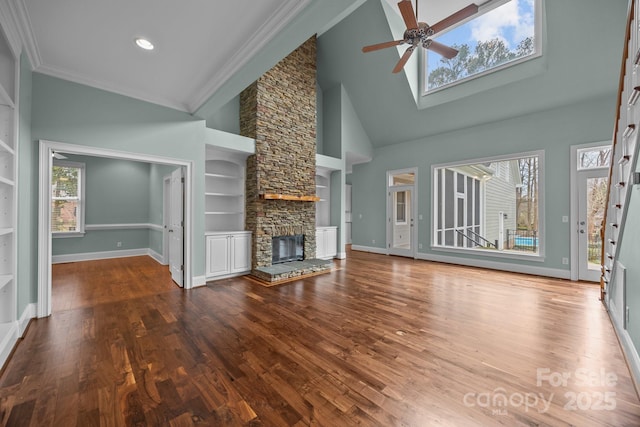 unfurnished living room featuring built in features, wood finished floors, a fireplace, baseboards, and ceiling fan