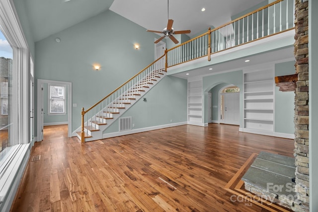 unfurnished living room with stairway, built in features, wood finished floors, visible vents, and baseboards