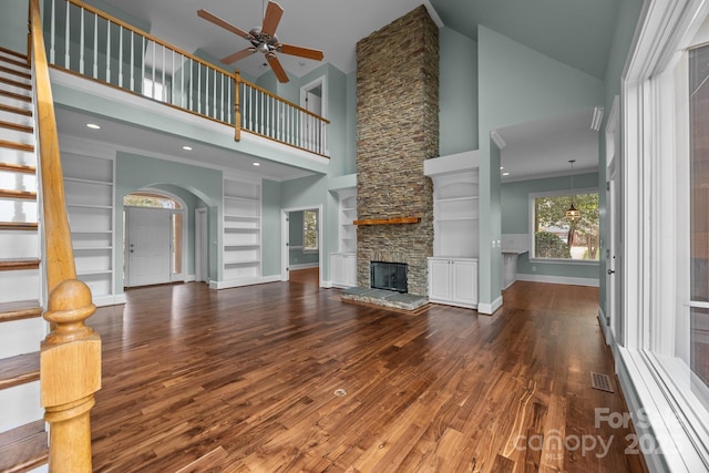 unfurnished living room featuring baseboards, built in shelves, wood finished floors, and a fireplace