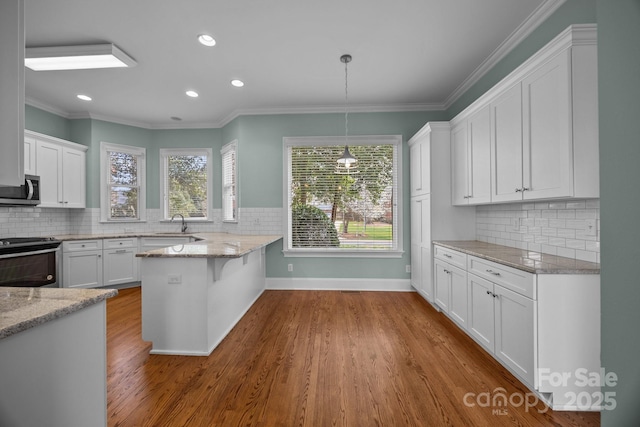 kitchen with stainless steel microwave, electric range oven, and white cabinetry