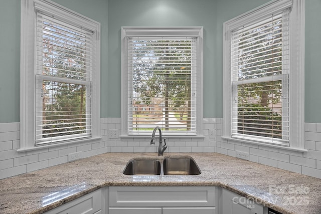 kitchen with white cabinetry, decorative backsplash, and a sink