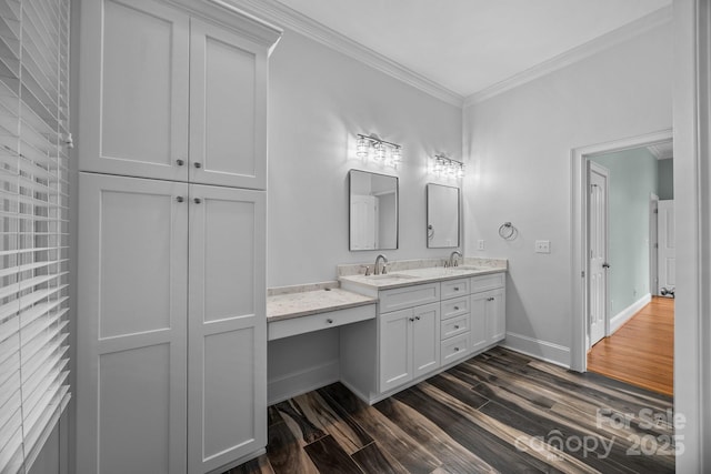 bathroom featuring crown molding, wood finished floors, baseboards, and a sink