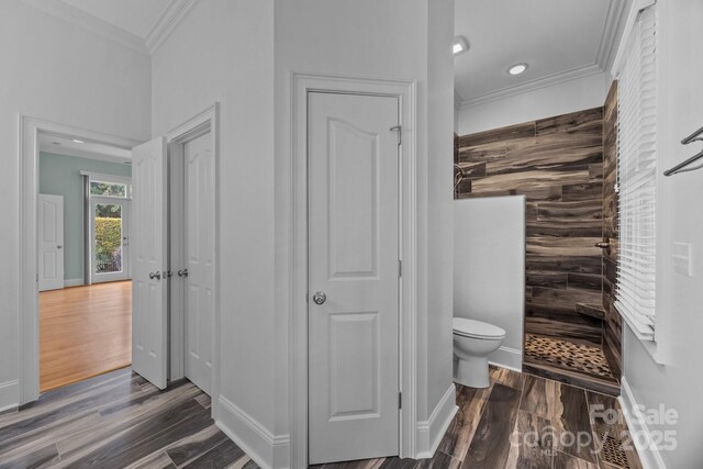 full bathroom with toilet, walk in shower, wood finished floors, and crown molding