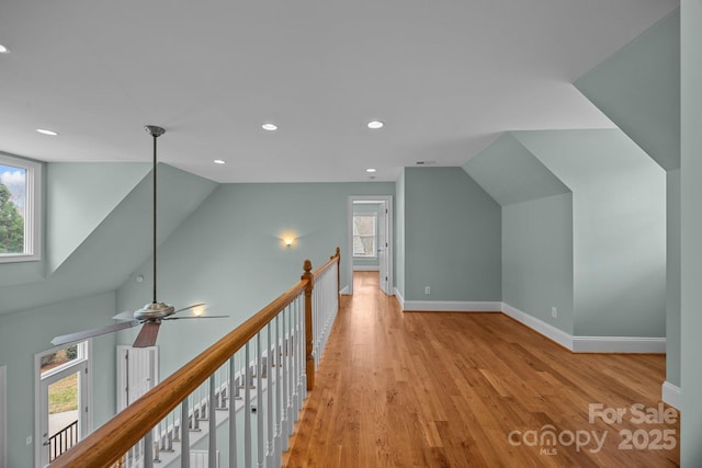 additional living space with vaulted ceiling, light wood-style flooring, a healthy amount of sunlight, and baseboards