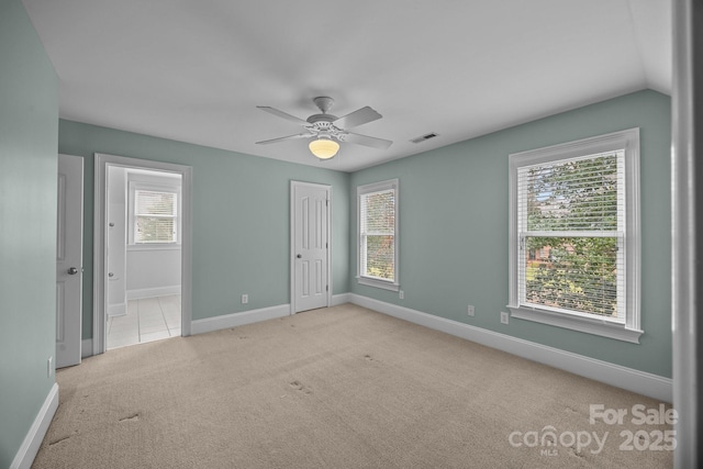 unfurnished room with visible vents, carpet floors, plenty of natural light, and baseboards