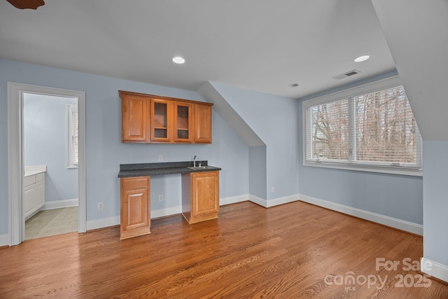 bar with visible vents, a sink, wood finished floors, recessed lighting, and baseboards