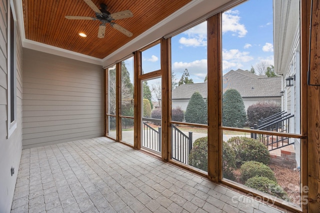 unfurnished sunroom featuring wooden ceiling and a ceiling fan