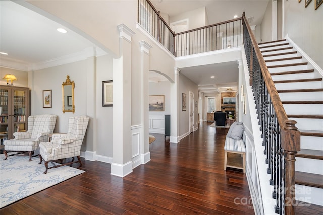 foyer entrance featuring hardwood / wood-style flooring, stairs, baseboards, and ornate columns