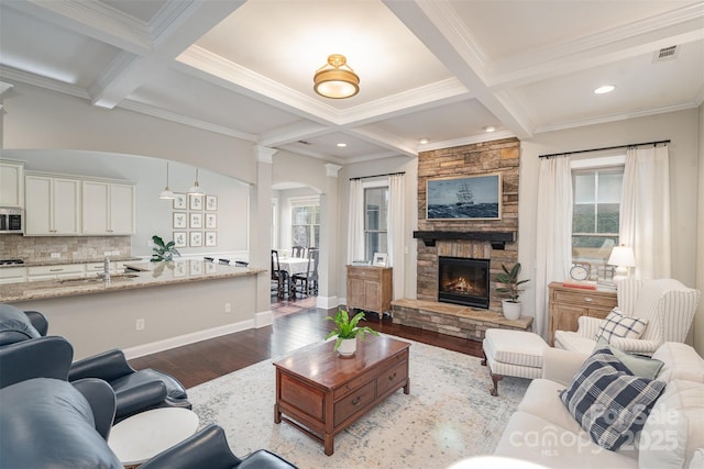 living area with beamed ceiling, coffered ceiling, and wood finished floors