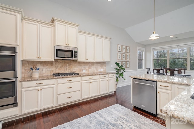 kitchen with lofted ceiling, appliances with stainless steel finishes, dark wood-type flooring, and light stone countertops